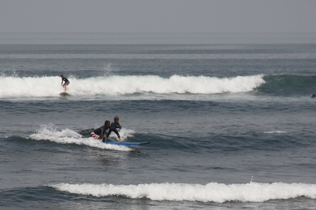 Oskar på longboard med surfinstruktør