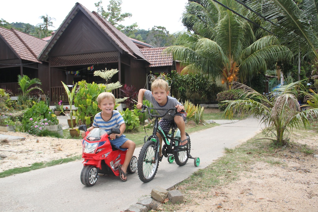 Alfred og Oskar cykler på stien foran hytten på Tioman