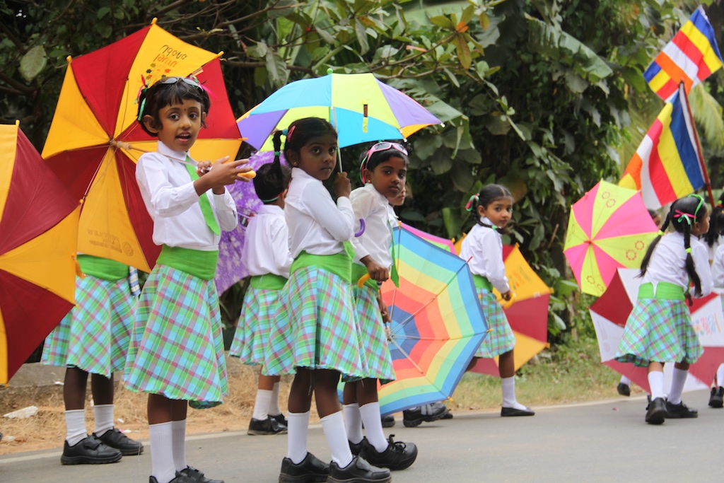 Børn i farverige kostumer med paraplyer